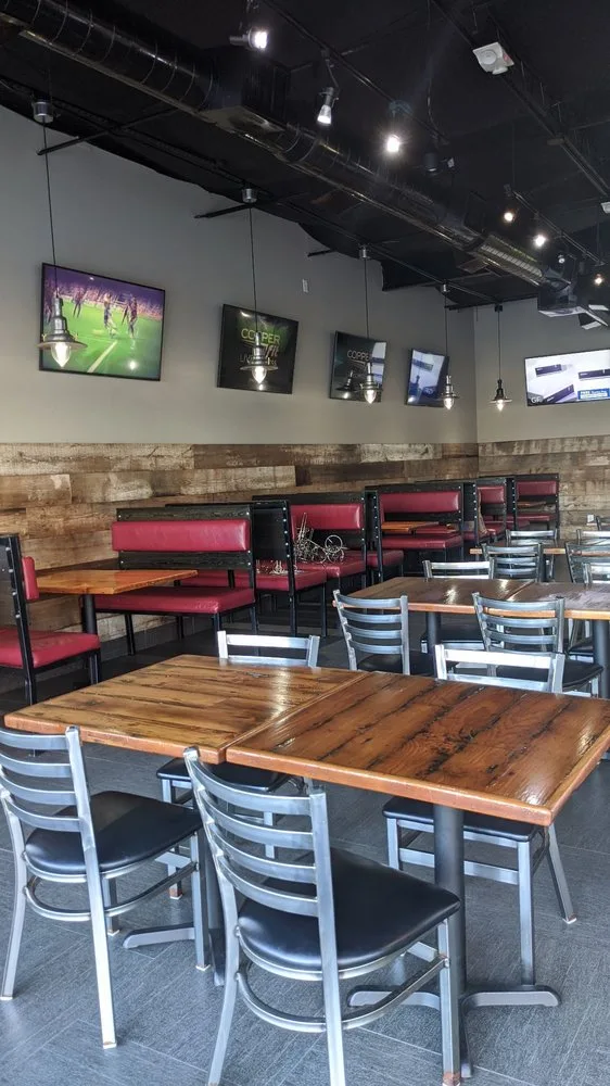 Tacos El Bigotes dining room with red booths, wood tables and TVs